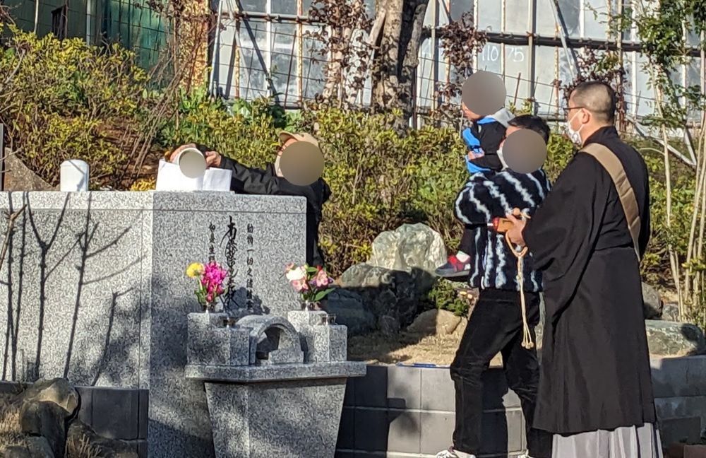 住職が合葬墓に手を合わせ、ご遺族様が納骨されている